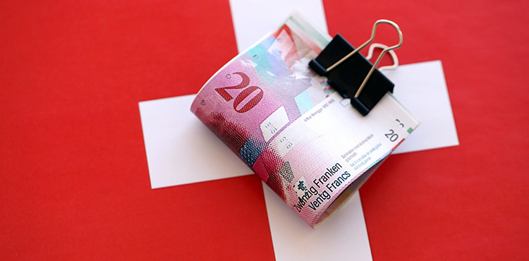 Ein Bündel 20er-Noten als Bargeld auf Schweizer Flagge