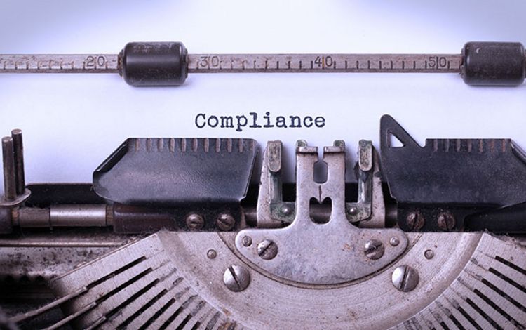 Alte Schreibmaschine mit Schriftzug Compliance auf eingespanntem Papier