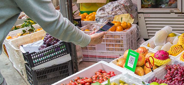 Mobile Zahlung mit WeChat, Hand mit Smartphone scannt einen QR-Code auf dem Markt