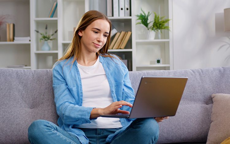 Junge Frau auf Sofa am Laptop