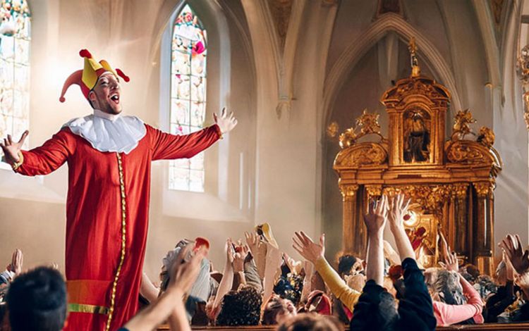 Bild mit einem Kasperli statt einem Priester und begeisterten Zuschauern
