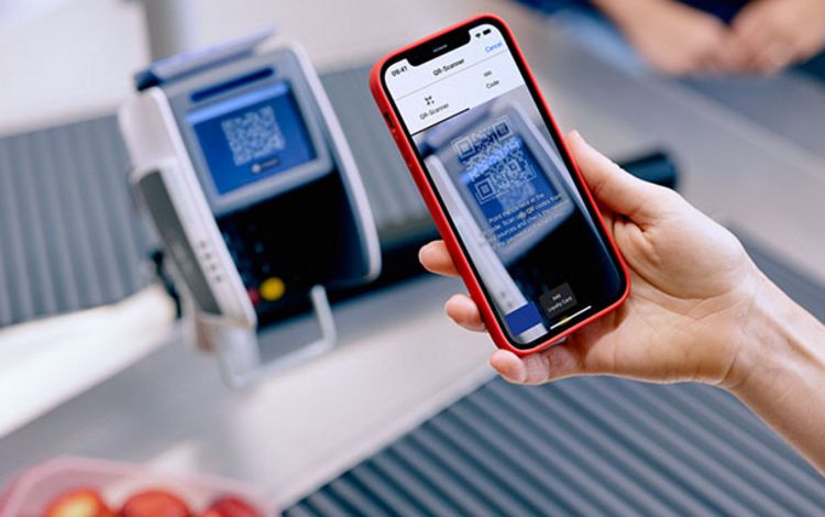 Frau mit Smartphone bezahlt an der Ladenkasse mit Twint