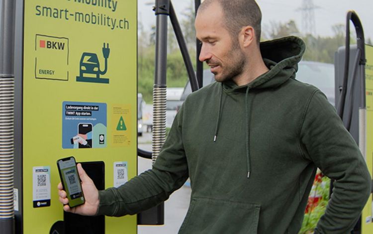 Junger Mann beim Auflagen seines E-Autos an einer Ladesäule